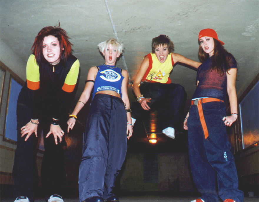 90s fashion included short and spiky hairstyles, baggy sports pants, a midriff top, a backwards baseball cap, and wristbands/armbands galore.